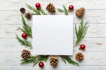 Flat lay Christmas composition. square Paper blank, pine tree branches, christmas decorations on Colored background. Top view, copy space for text