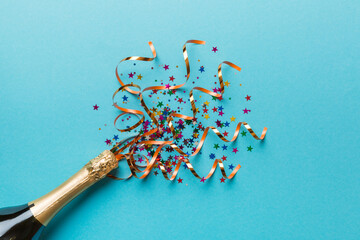 Creative flat lay composition with bottle of champagne and space for text on color background. Champagne bottle with colorful party streamers. holiday or christmas concept