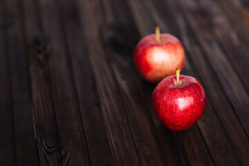 Two red apples on a wooden table	