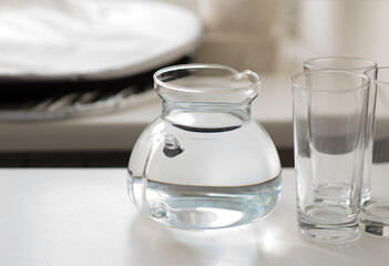 Glass jug with water and glasses for water in the kitchen
