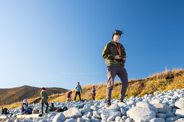 A drone pilot wearing virtual reality glasses is piloting an unmanned aerial vehicle using a remote control. A man in a virtual reality helmet during a photo and video shooting in a hike in nature.