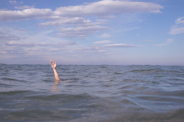 Person submerged on a beach with hand out pretending to be drowning