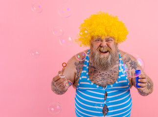 Amazed man with yellow wig in head play with bubbles soap
