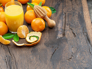 Orange tangerine fruits and glass of fresh tangerine juice on dark wooden background.