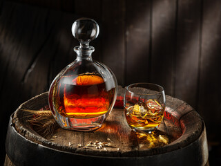 Carafe of whisky and glass of whisky on old wooden cask at the dark background. - obrazy, fototapety, plakaty