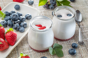 Two glass containers with plain yoghurt and berries on the table. Light summer mood.