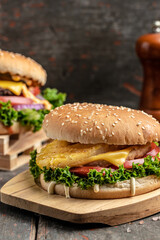 Homemade burger with grilled beef meat, vegetables, sauce on rustic wooden background. fast food and junk food concept