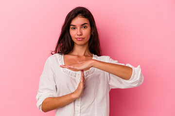 Young caucasian woman isolated on pink background showing a timeout gesture.