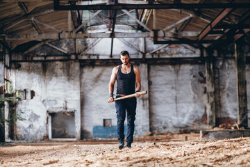 Strong Muscular Handsome Man in Black Tank Top with Baseball Bat Walksin Empty Grunge Hall
