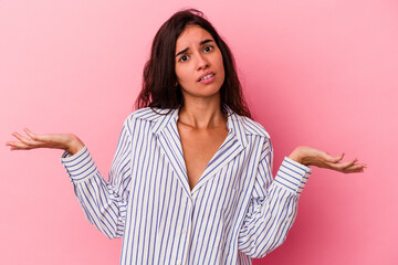 Young caucasian woman isolated on pink background doubting and shrugging shoulders in questioning gesture.