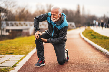 Active senior man is having pain in knee while jogging. - obrazy, fototapety, plakaty