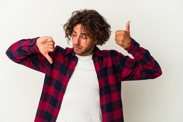 Young caucasian man isolated on white background showing thumbs up and thumbs down, difficult...