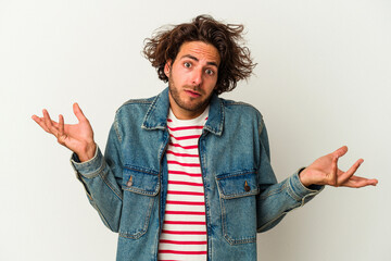 Young caucasian man isolated on white background doubting and shrugging shoulders in questioning...