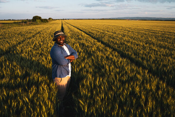 Farmer is standing in his growing wheat field. He is satisfied after successful sowing.