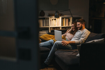 happy young couple enjoying time at home using laptop computer