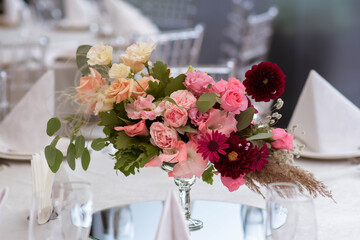 White tablecloths with clear vases and colourful flowers arrangements. Golden colored plates, peavh...