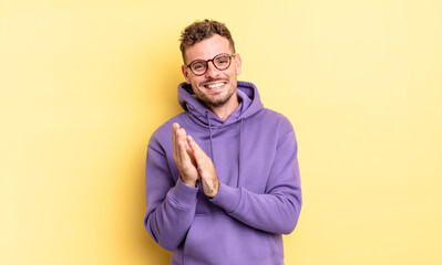 young handsome hispanic man feeling happy and successful, smiling and clapping hands, saying...