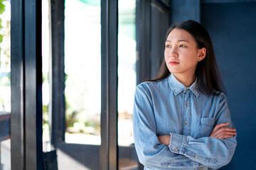 Portrait of an Asian attractive Modern businesswoman standing in the office wearing a blue shirt,...