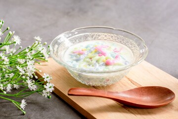 Thai dessert. Colorful of cendol with coconut milk in a clear bowl on a dark table. Delicious famous sweet dish in Thailand.