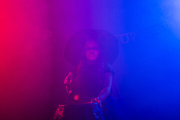 Little witch child cooking potion in the cauldron on Halloween.