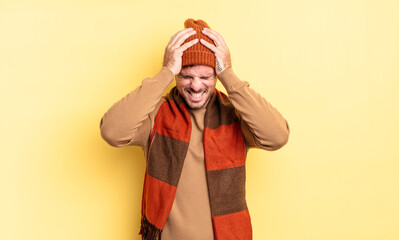 young handsome hispanic man feeling stressed and frustrated, raising hands to head, feeling tired,...