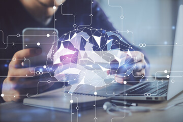 Double exposure of man's hand holding and using a digital device and brain hologram drawing. Data...
