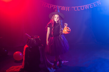 Little girl holds pumpkin jack on Halloween holiday. Kid girl wear witch costume. Fantasy, fairy tale and masquerade concept.