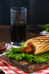 French hot dog with herbs and a drink in rustic style. Street food.