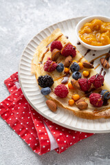 Close up of crepes with berries and sauce on white plate