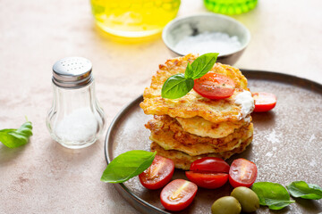 Stack of potatoes fritters served with cherry tomato and olive