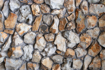 Background with different brown and grey colored rough rock stones textured wall. Close up.