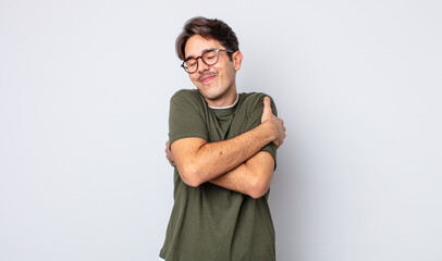 young handsome hispanic man feeling in love, smiling, cuddling and hugging self, staying single,...