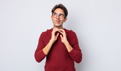 young handsome hispanic man scheming and conspiring, thinking devious tricks and cheats, cunning...