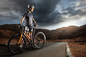 Sport. The cyclist rides on his bike at sunset. Dramatic background. - obrazy, fototapety, plakaty