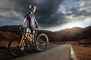 Foto op Plexiglas Sport. The cyclist rides on his bike at sunset. Dramatic background. © vitaliy_melnik