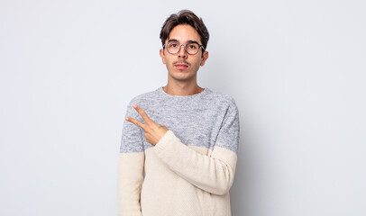 young handsome hispanic man feeling happy, positive and successful, with hand making v shape over...