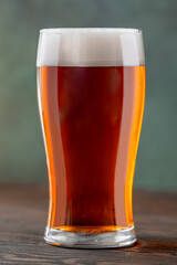 Pint glass of fresh beer on dark background