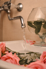 Glass of wine and bouquet of pink roses in sink