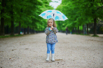 Child wearing rain boots with umbrella on a fall day