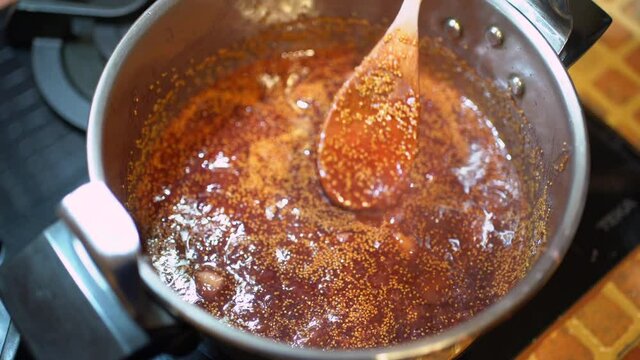 Crop person preparing fig jam in pressure cooker in kitchen