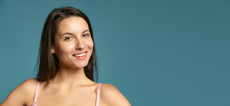 Close-up portrait of young beautiful girl without makeup isolated over blue studio background. Natural beauty concept.
