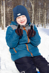 boy smiling sitting on a snowdrift