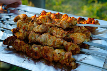Ready fried delicious juicy kebab on skewers lies on a large platter and smokes