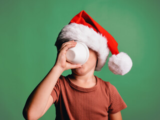 Boy in Santa hat drinking from cup in studio