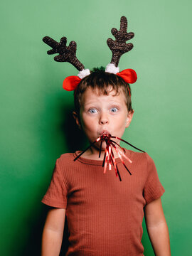 Boy in deer antlers headband blowing noisemaker
