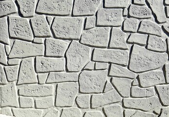 Gray concrete wall with forms of fake decorative rocks carved on the surface. Background and...