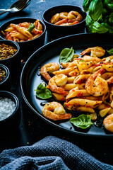 Penne with fried prawns in on black wooden background
