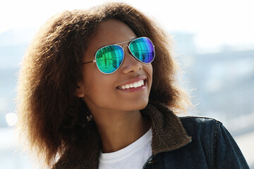 pretty woman wearing sunglasses with perfect teeth and dark clean skin having rest outdoors