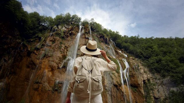 Attractive traveler at the cascade of the waterfall on the mountain