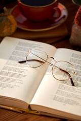 reading, season and leisure concept - close up of open book of poems and glasses at home in autumn